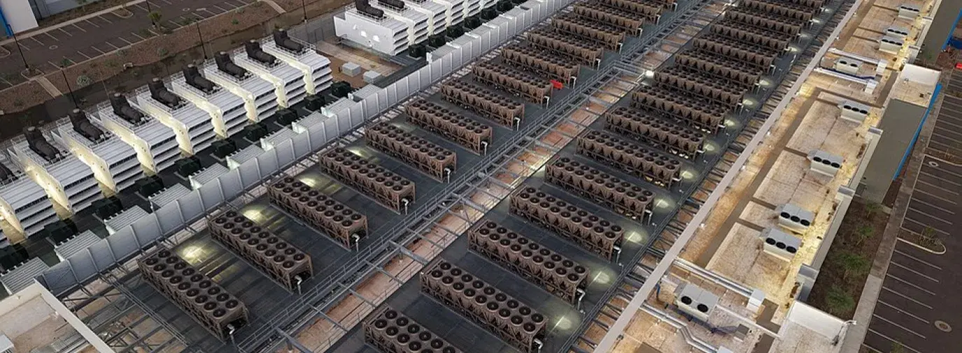 Aerial view of a large data center rooftop covered with rows of industrial cooling units.