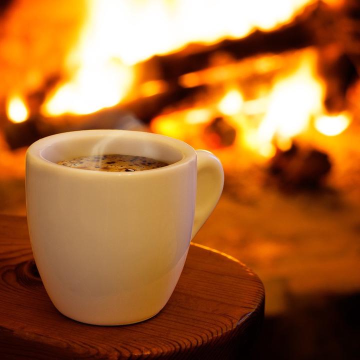 cup of steaming drink in front of a fireplace