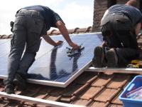 workers attaching solar panels to a house