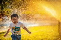 Image: child playing in water sprinkler. Title: 13 Ways to Save More than 65 Gallons of Water a Day