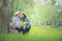 man and woman with hats standing in grass. 