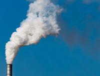 smoke billowing out of a factory chimney against a blue sky