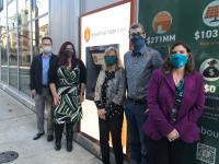 Five masked employees at Beneficial State Bank stand next to an ATM