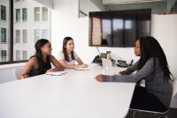 Two Black women and a fair-skinned woman sitting at an office table