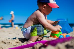 Image: child playing with toys in the sand. Title: Green Your Holidays: Avoiding Toxic Toys