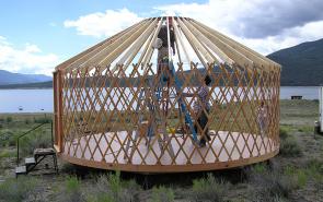 man standing inside yurt construction.