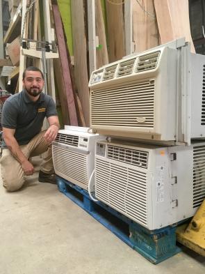A Community Forklift staff member with a pallet of salvaged window A/C units