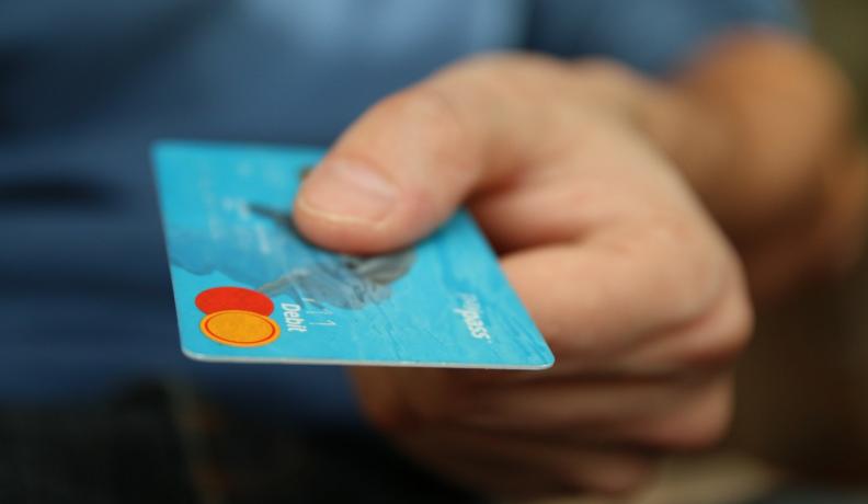 Image: person handing over a credit card. Topic: responsible credit cards