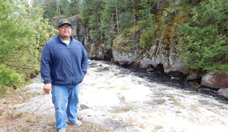 Guy Anahkwet Reiter stands near the Menominee River, which is sacred to the Menominee Tribe.