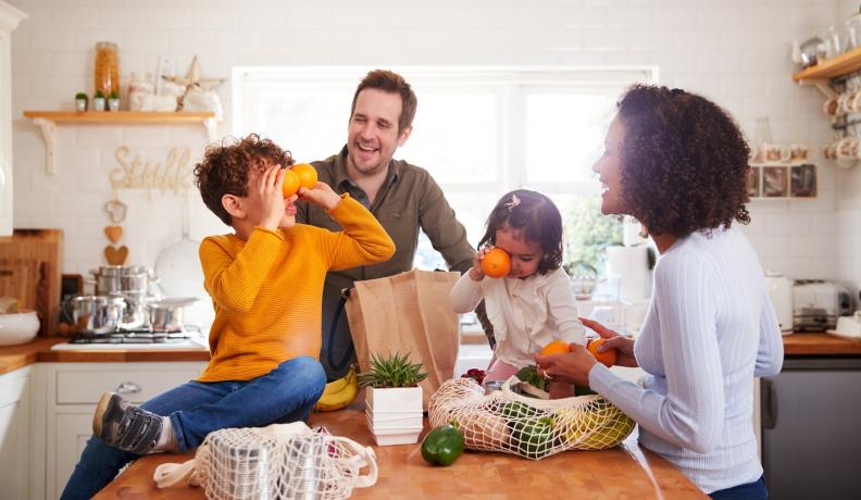 family laughing around a counter with groceries on it