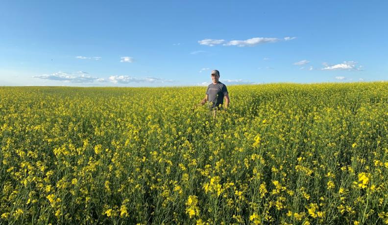 Tyler Streit smiling in a field of mustard flowers