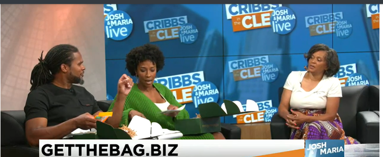 Gloria Ware, a Black woman, sits on the far right, being interviewed at a local TV news station. On the left, a Black man and Black Woman interview her.