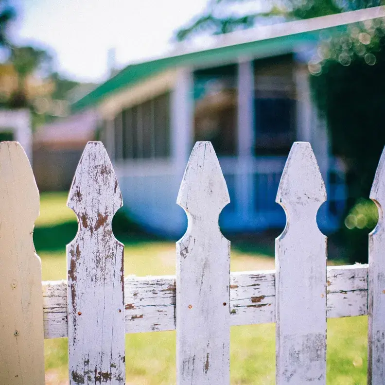 Image: picket fence in front of a home. Topic: Mortgages from Responsible Banks and CDFIs