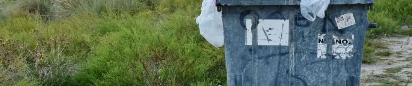 Bin filled with garbage in a field, zero waste is the goal