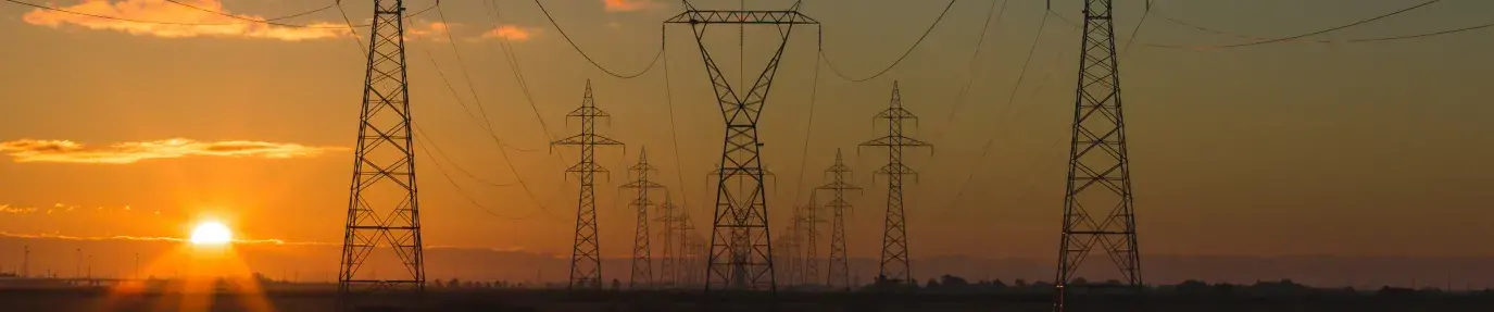 Sunset behind power lines and towers, which do not prioritize energy efficiency
