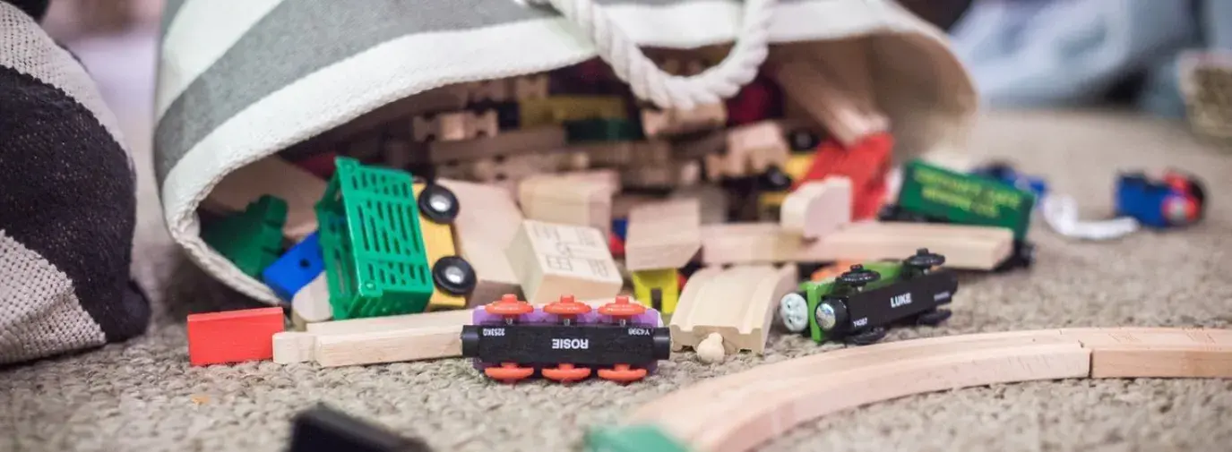 a bag of wooden toys by a train set