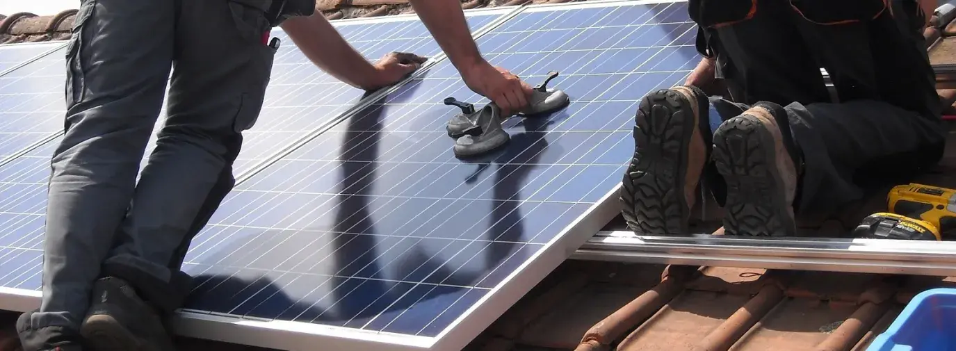 Image: workers attaching solar panels to a house. Title: Make Solar Power Affordable Now