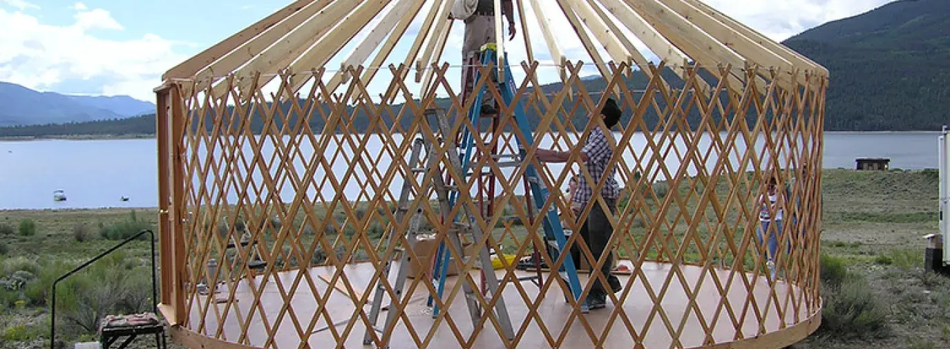 man standing inside yurt construction.