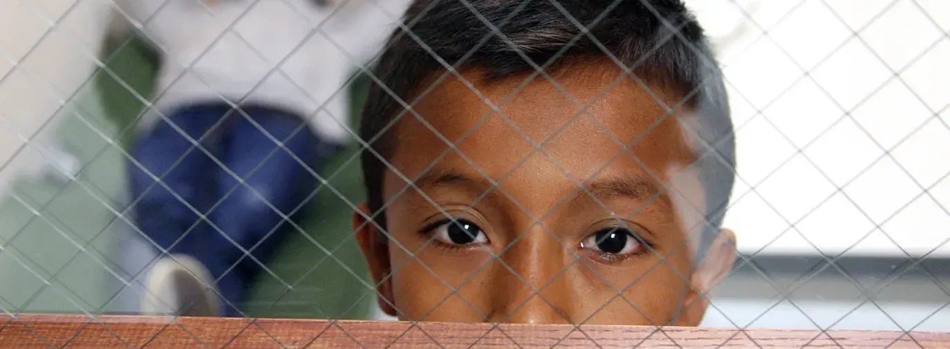 immigrant boy behind fenced glass