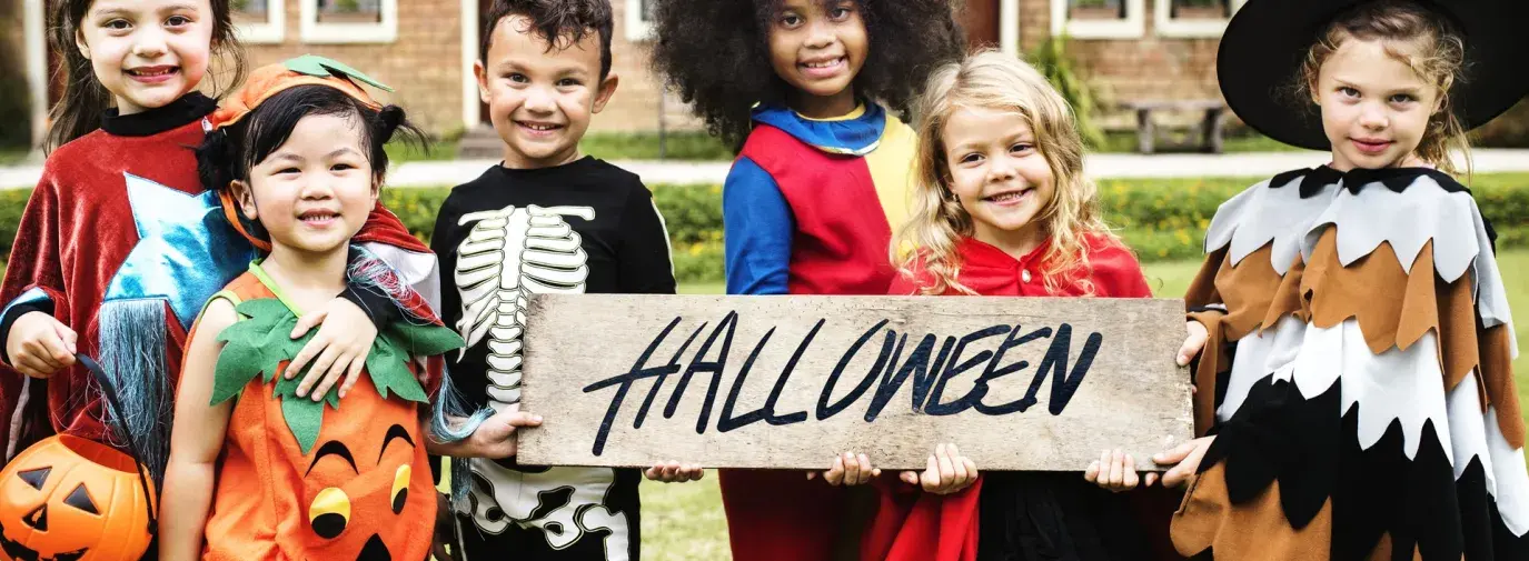 Image: children in Halloween costumes holding sign, "Halloween." Title: Is There Child Labor in Your Halloween Candy? Chocolate Scorecard Identified Good, Ghoulish Companies