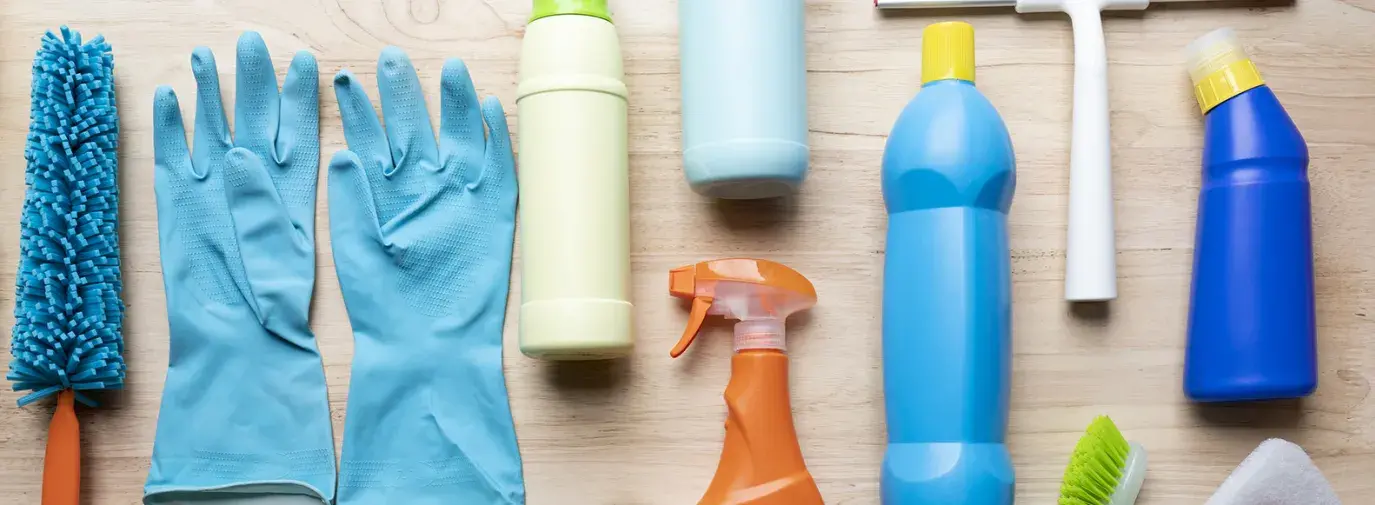 Image: an array of cleaning products on a table. Topic: 13 Toxic Chemicals Lurking in Your Home