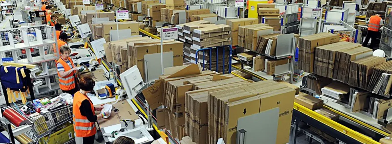 Image: Amazon workers packaging items in a warehouse. Topic: Why We Should Quit Amazon