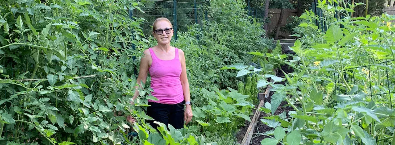 woman in pink shirt stands in lush home garden