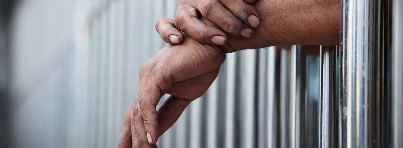 hands hanging out of a prison cell