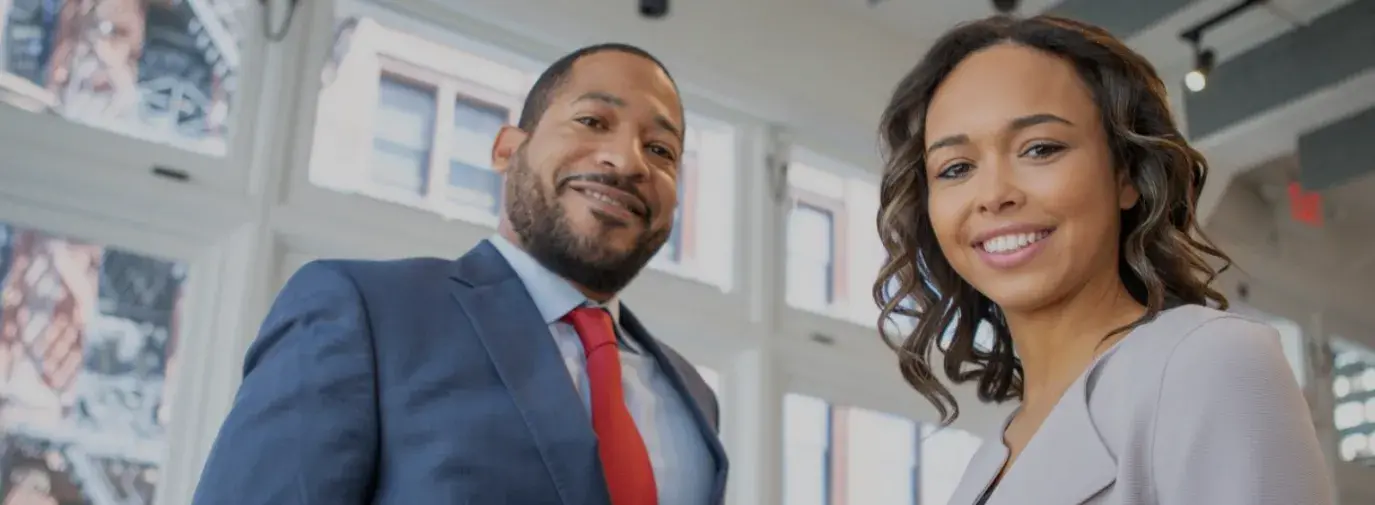 black man and black woman in business attire looking at the camera