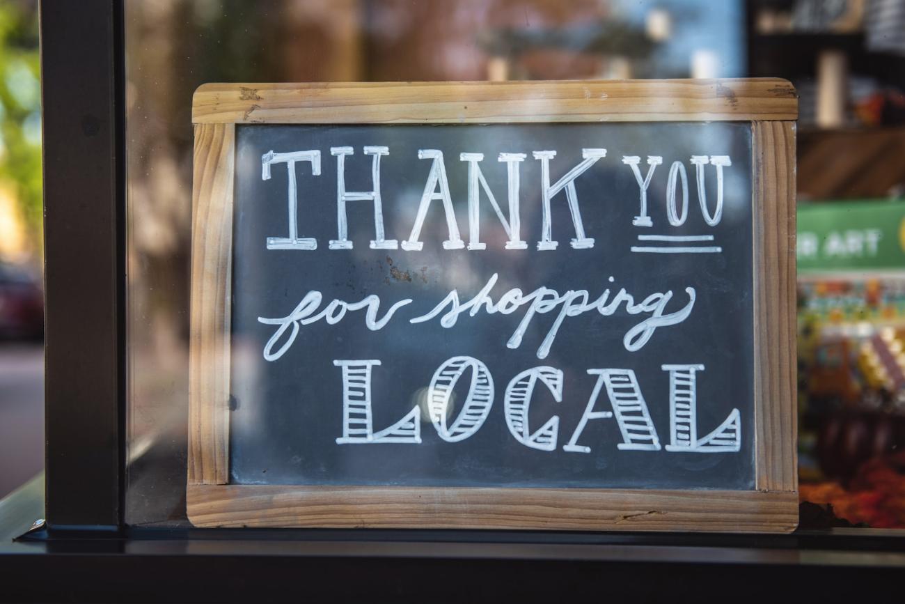 Close-up of a chalkboard sign in a shop window, it reads: "Thank you for shopping local." Ethical Shopping Resolutions.