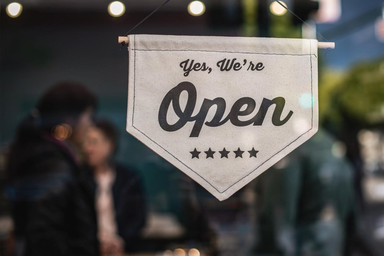 A sign hanging in a window that reads: "Yes, we're open"