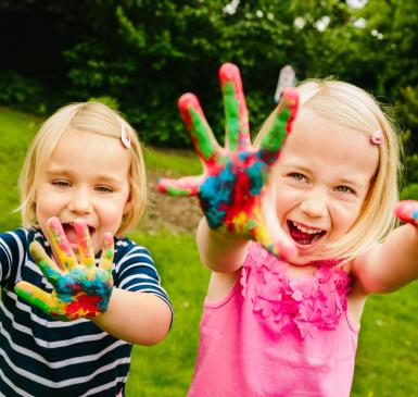 Image: kids playing, with paint on their hands. Title: Green Kids