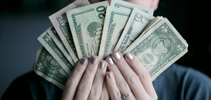 Image: person holding American currency. Title: Divest & Reinvest 