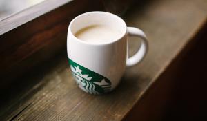 Image: milk in a Starbucks mug. Title: Why is Starbucks’ milk an environmental issue?