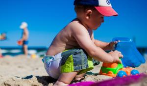 Image: child playing with toys in the sand. Title: Green Your Holidays: Avoiding Toxic Toys