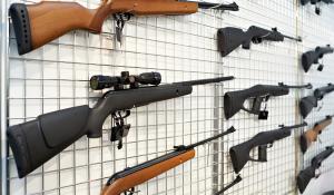 Image: guns on a rack. Title: Are You Unintentionally Investing in Gun Manufacturers?