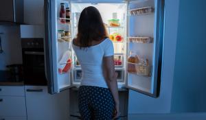 Image: woman looking in fridge at night. Topic: 5 Ways to Fight Food Waste