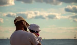 Black dad and daughter looking towards the bay