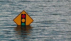 image of a traffic light sign mostly underwater thanks to flooding.