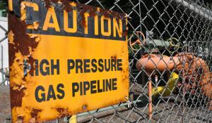 Image yellow sign reading "Caution: High Pressure Gas Pipeline." Topic: Natural Gas Pipeline and Infrastructure Explosions Nationwide