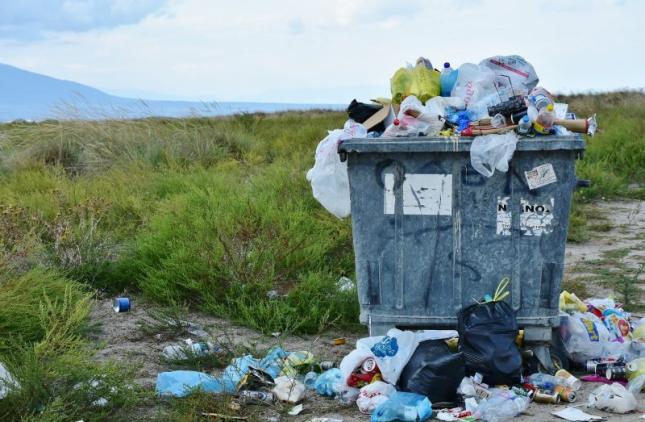 Bin filled with garbage in a field, zero waste is the goal