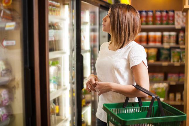 woman in grocery store standing in front of a refrigerator 