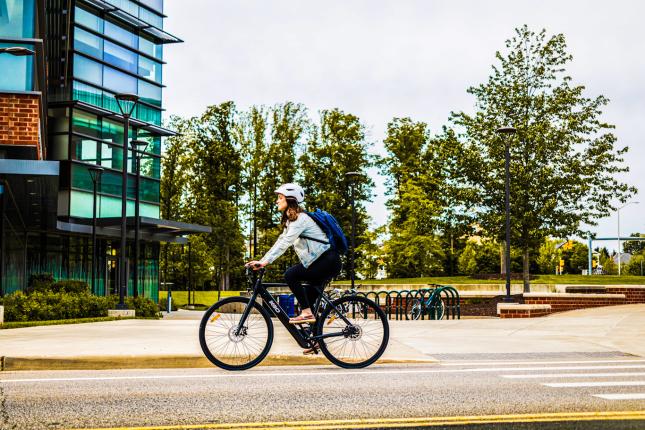woman riding bicycle with helmet and backpack on, many americans choose bike commuting to work