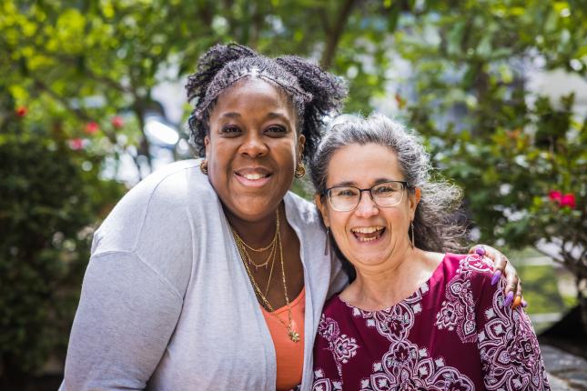 Dr. Lakeisha Thorpe, a Black woman, wears a light grey cardigan over a peach colored shirt. She stands next to Fran Teplitz, retiring co-executive director of Green America, a white woman with greying hair, glasses, in a burgundy floral top.