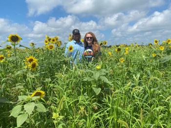Nebraska farmers Brian and Liz James are standing in a field of sunflowers smiling at the camera.